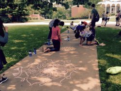 Kids draw on a sidewalk with chalk.