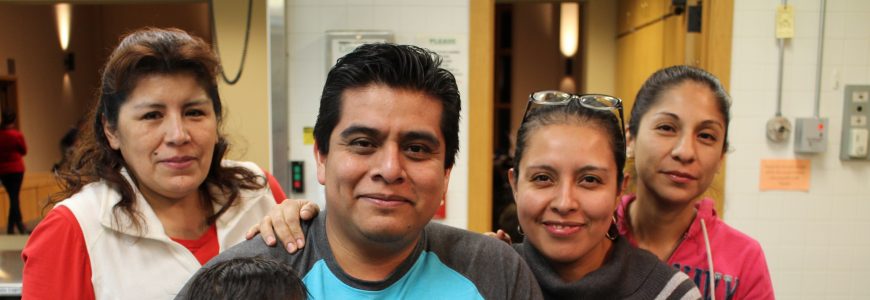 A family poses smiling with their newborn child.